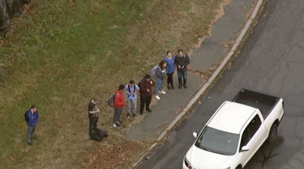 Crash involving a school bus and a car in Danvers.   Many of the students who were on the bus are   standing on side of road.  