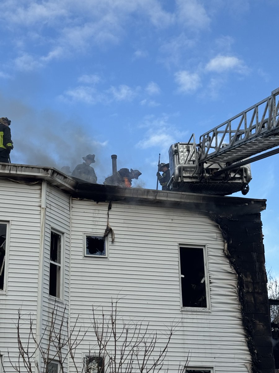 Firefighters continue to chase the fire in the eaves and roof at the 2 alarm fire on Washington st Roslindale.This is a 3 family home
